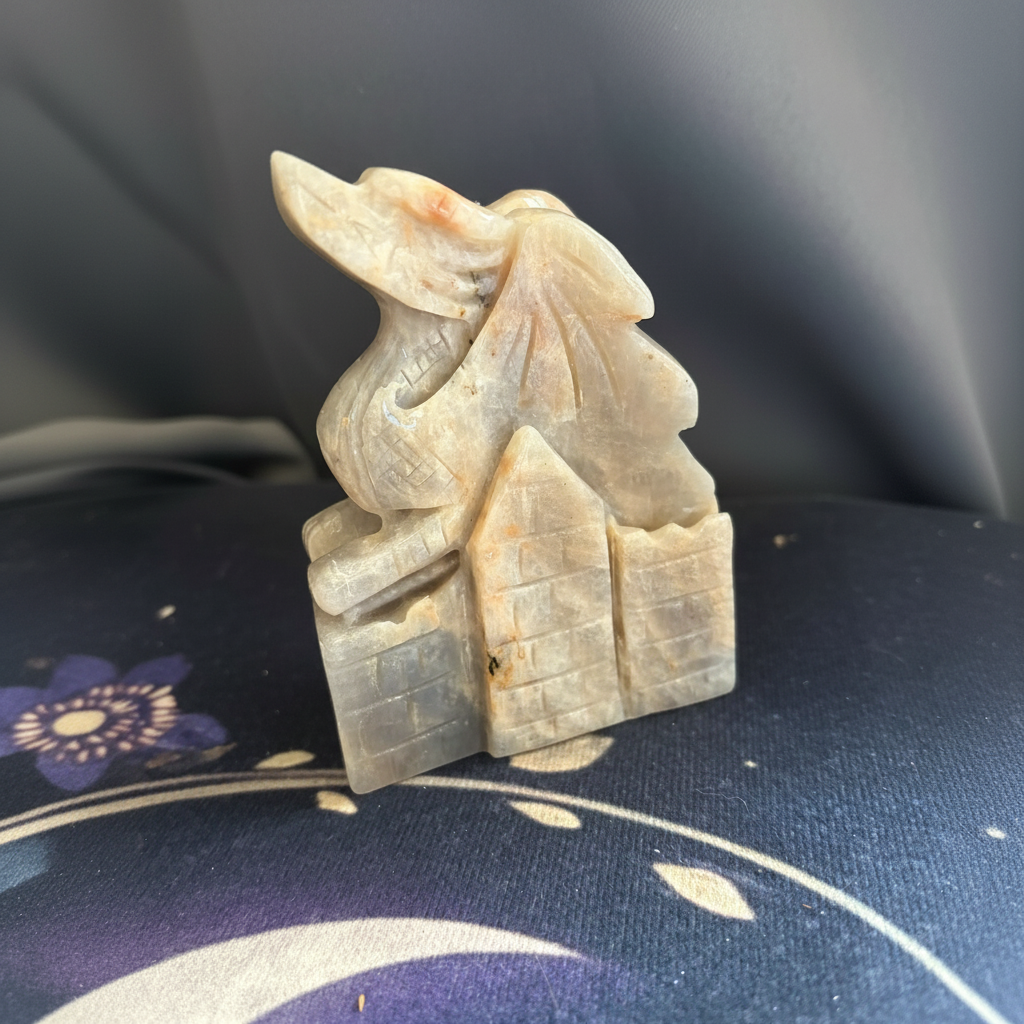 Hand-carved moonstone dragon and castle ornament from an angled view