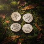 Four rustic wood slice garden quote coasters arranged on a dark moody forest floor with moss, ferns and autumn leaves