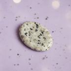 Dalmatian Jasper palm stone on pale purple background with scattered silver stars