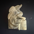 Hand-carved moonstone dragon curled around a castle, front view
