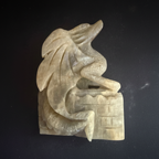 Hand-carved moonstone dragon curled around a castle, front view