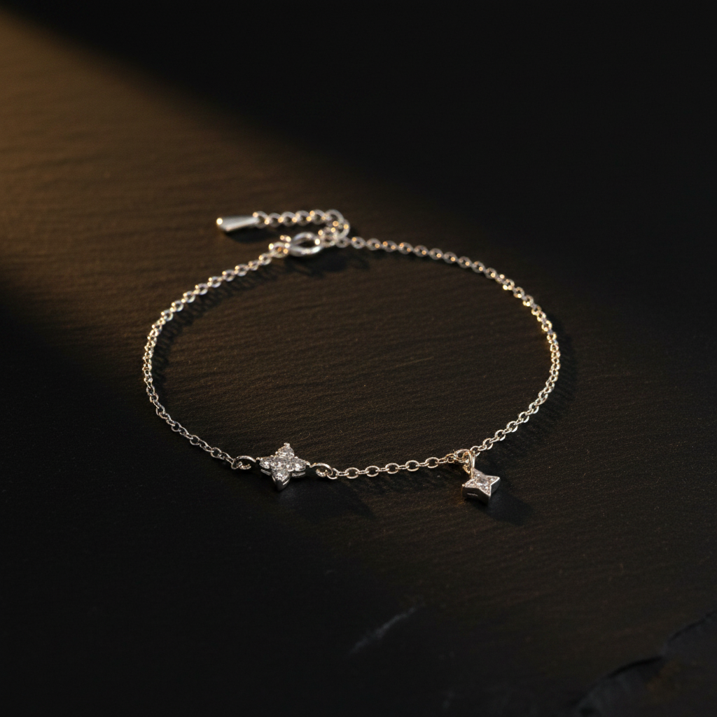 Sterling silver dual CZ star bracelet laid on a dark moody surface with soft dramatic lighting, showing two four-pointed star charms on a fine cable chain