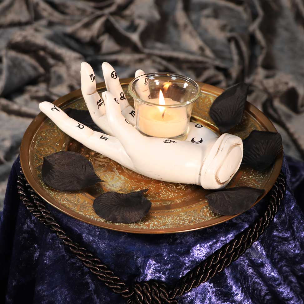 Palmistry Hand Tealight Candle Holder - moody lifestyle shot with lit candle on gold tray with black rose petals