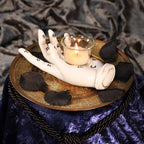 Palmistry Hand Tealight Candle Holder - moody lifestyle shot with lit candle on gold tray with black rose petals