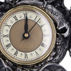 Close-up of Roman numeral quartz clock face with skull detail