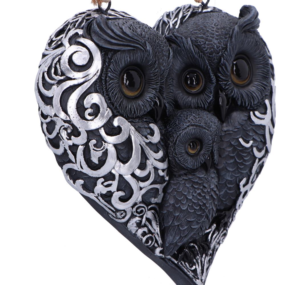 Owl family heart wall hanging displayed on dark tree bark at night